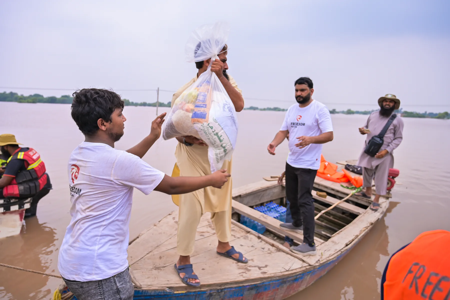 Relief workers passing supplies to a person in a boat
