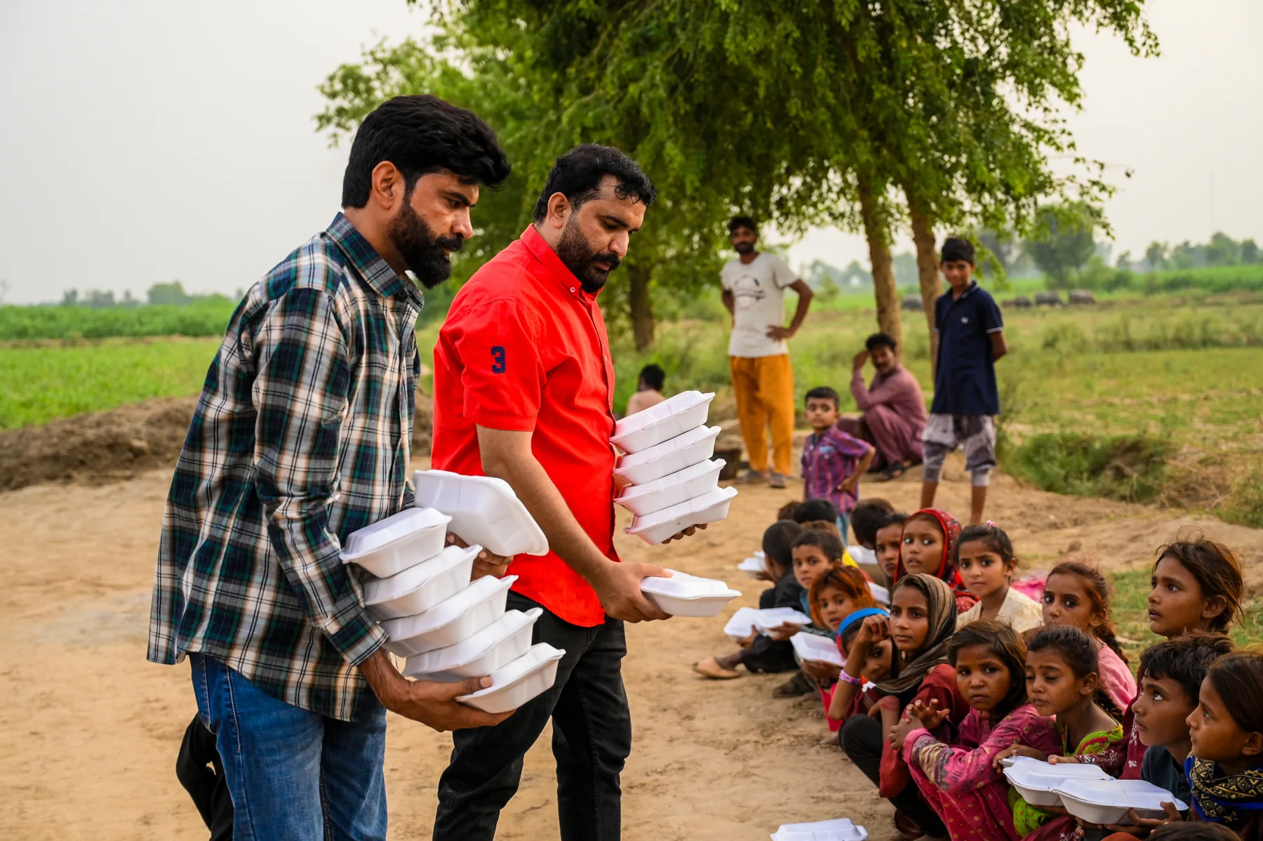 Volunteers sharing meals with children outdoors